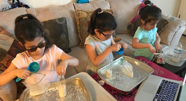 Three young sisters work together on a project.
